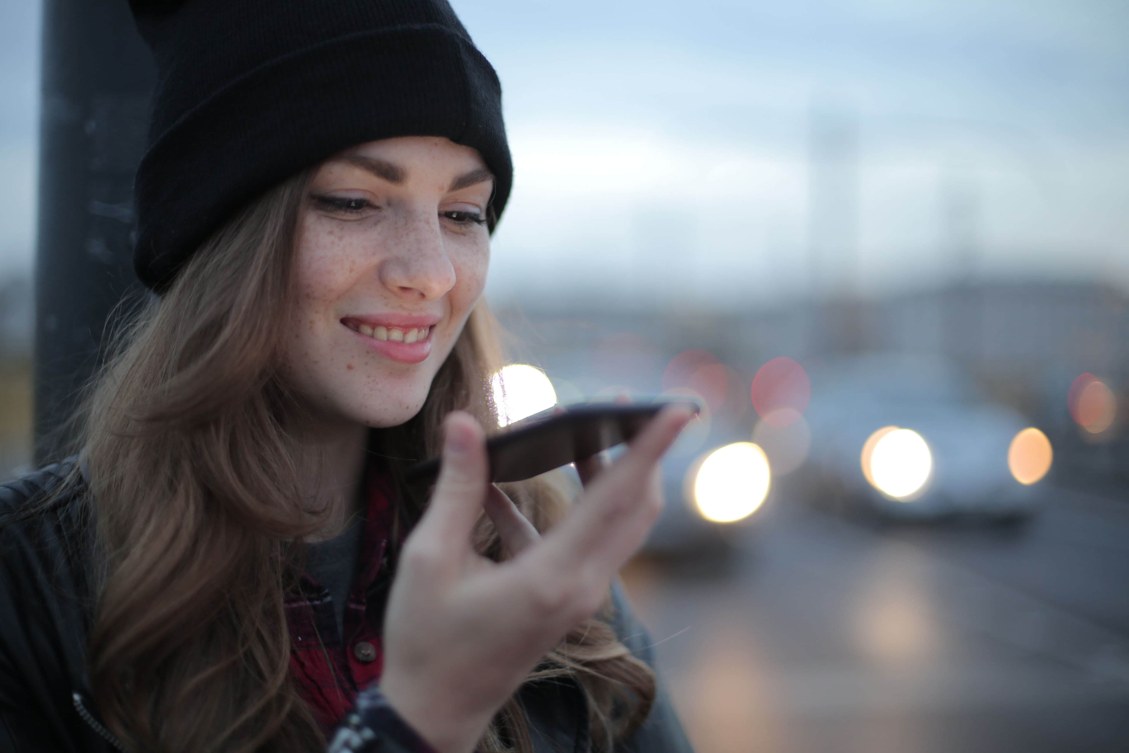 Frau spricht mittels Sprachassistenten etwas in ihr Smartphone